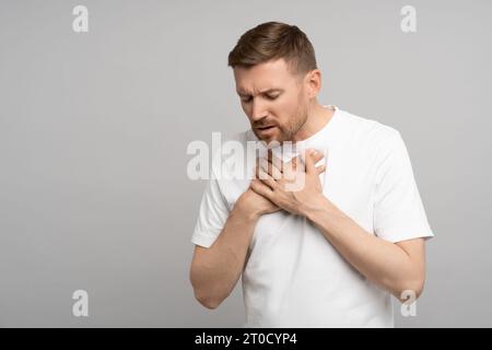 Man holds on to chest, suffering from heartburn. Acute discomfort, pain in sternum.  Stock Photo