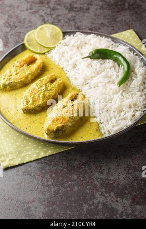 Hilsa fish cooked with mustard and traditional Bangladeshi spices served with white rice closeup on the plate on the table. Vertical Stock Photo