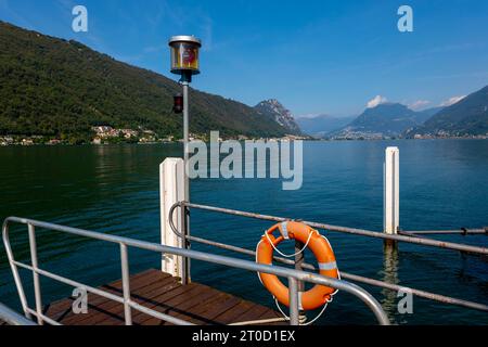 Pier in Brusino Arsizio on the Waterfront in a Sunny Summer Day on Lake Lugano and Mountain in Brusino Arsizio, Ticino, Switzerland Stock Photo