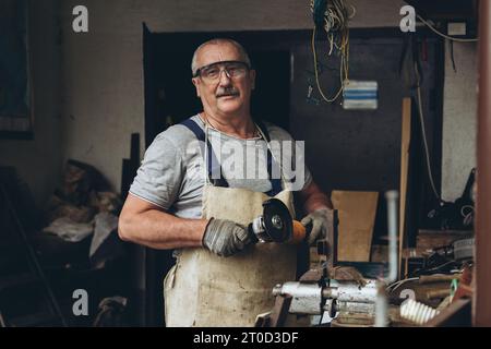 Smiling man stands in the workshop with a tool in his hands Stock Photo