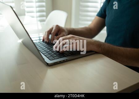 Man types on laptop, wears silicone wedding ring Stock Photo