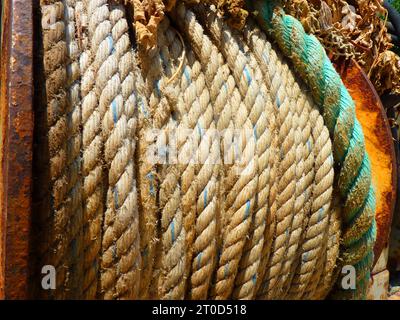 Metal rusting bollard with heavy green ropes on a ship. Stock Photo