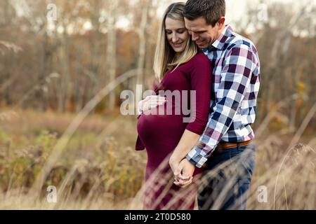Close up photo of pregnant couple holding hands in a field Stock Photo