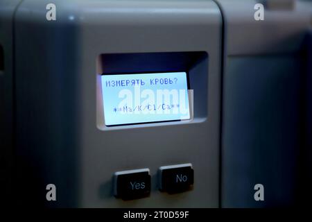 Measuring laboratory instrument. A device for analyzing blood. The inscription on the screen of the device in Russian: "To measure blood? Yes. No." Stock Photo
