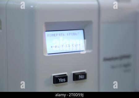 Measuring laboratory instrument. A device for analyzing blood. The inscription on the screen of the device in Russian: "To measure blood? Yes. No." Stock Photo