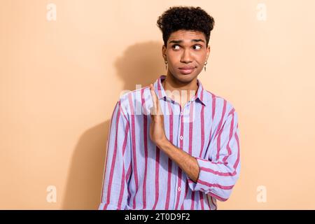Portrait of serious young guy hold hand palm straight to empty space express negative attitude isolated beige color background Stock Photo
