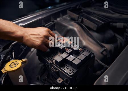 Male auto-mechanic changing relay and checking operation of the fuses Stock Photo