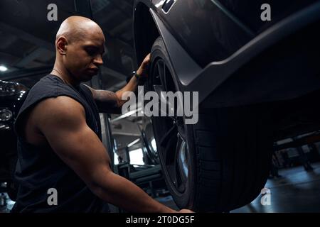 African American auto-mechanic changing seasonal tires and doing tire balancing Stock Photo