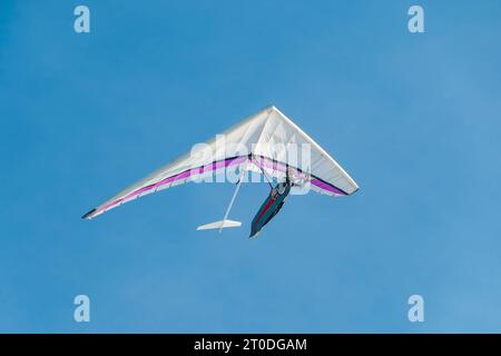 Hang glider pilot soaring in the blue sky. Extreme airborne sport Stock Photo