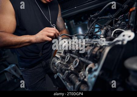 African-American auto-mechanic engaging in car engine repairing Stock Photo