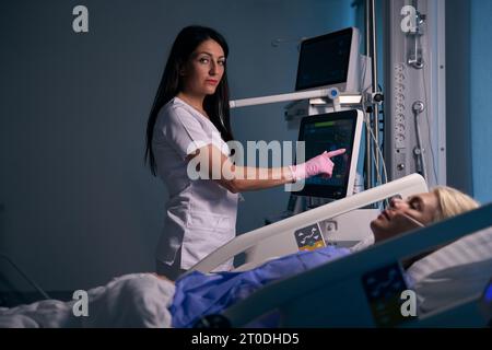 Female medical worker uses modern equipment in the recovery room Stock Photo