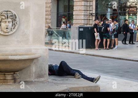Homeless man sleeping on a fountain, Ferenciek tere square, Budapest, Hungary Stock Photo