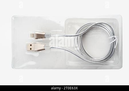 Silver-colored USB cable in plastic packaging on a white background. Copy space. Stock Photo