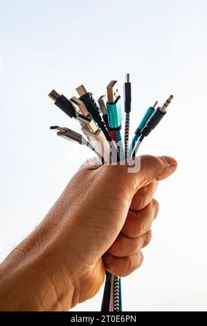 Hand holding various types of cables with USB plugs, evolution and change of USB connections. Stock Photo