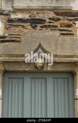 Angers, France, 2023. A medieval sculpted head (mascaron) on the lintel of the door leading inside one of the turrets of the châtelet (vertical) Stock Photo