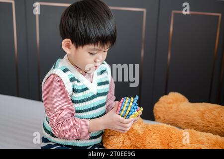 Asian boy playing with jigsaw puzzles on the bed joyfully Stock Photo