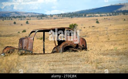 Remains of an old auto rusts on the Central Plains of Oregon.  Frame is all that is left and it is rusting and collapsing. Stock Photo