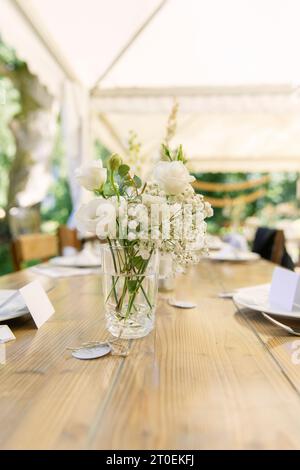 Wooden table set with white bouquet of flowers Stock Photo