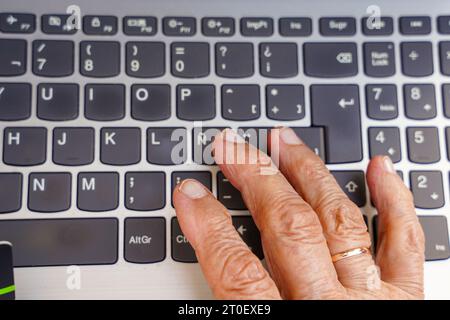 unrecognizable older woman typing on the keyboard in the computer. technology in elderly. Stock Photo