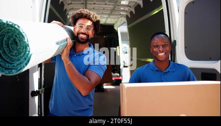 Movers Doing Furniture And Carpet Removal From Truck Or Van Stock Photo