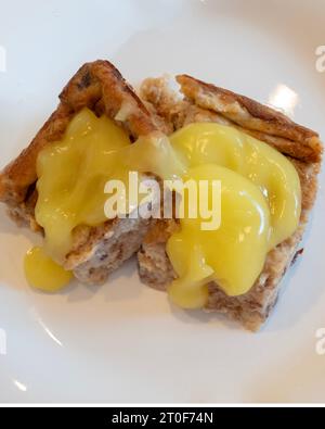 Bread pudding made with cinnamon raisin bread, eggs, sugar & milk, then baked. Topped with lemon sauce. USA. Stock Photo