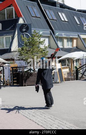 Person with snow clothes and skis walking through the city, in Pradollano, Granada, Spain Stock Photo