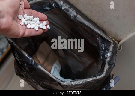 Throwing pills into the garbage - illegal disposal Stock Photo