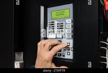 Technician using fire alarm control panel in service room. Single-stage fire alarm system in strata, residential or commercial building. Yearly checku Stock Photo