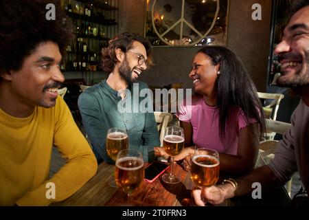 Group of young friends having beer in a bar and smiiling Stock Photo