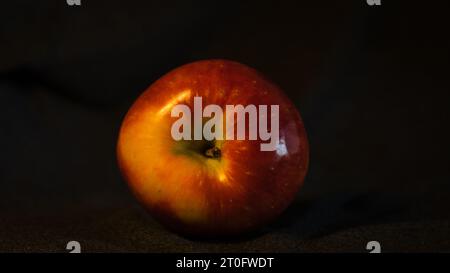 A crisp apple, a symbol of good health and wellness, set against a grey-black backdrop, inviting you to savor nature's goodness. Stock Photo