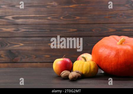 Happy Thanksgiving day. Fresh pumpkins, walnuts and apples on wooden table, space for text Stock Photo