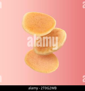 Tasty fresh pancakes falling on red background Stock Photo