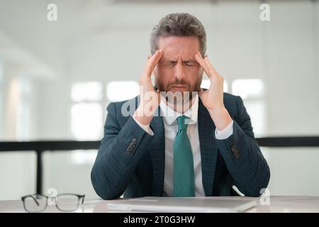 Tired, headache and eye strain from laptop. Businessman with stress, burnout and fatigue eyestrain. Business man rubbing tired eyes after computer Stock Photo