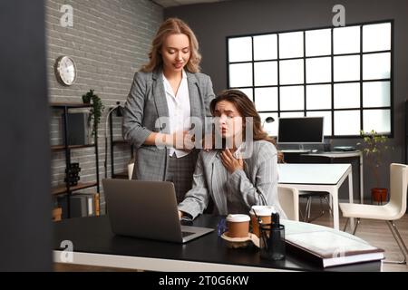 Woman helping her colleague who is having panic attack in office Stock Photo