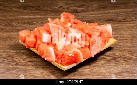 Peeled watermelon is red and fresh served on a wooden plate on a wooden table Stock Photo