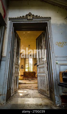wooden doorway with an old sofa in an abandoned mansion Stock Photo