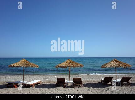 Loungers under palm tree leaves parasols on beach on Samos island, Greece Stock Photo