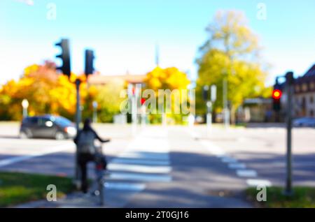 Defocused blurred photo of pedestrian crossing street and yellow autumn trees out of focus, Bokeh background Stock Photo