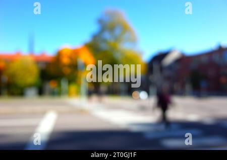 Unfocused blurred photo of people crossing street on zebra and yellow autumn trees out of focus, Bokeh background Stock Photo