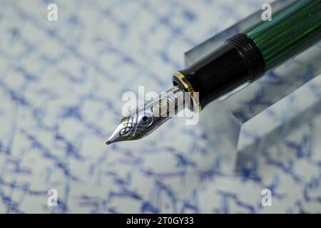 Itterbeck, Germany Oct 3 2023 Pelikan Souveraen M600 Fountain Pen. A blurred handwritten text in the background. Stock Photo