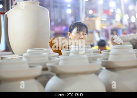 CHONGQING, CHINA - OCTOBER 7, 2023 - A worker colors a wine jar with flowers in a ceramic production workshop on October 7, 2023, Chongqing, China. Stock Photo