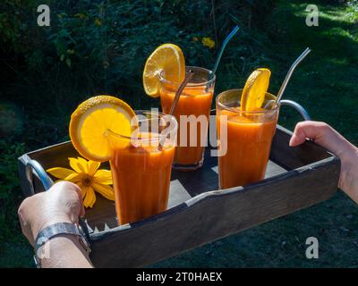 Freshly squeezed juice in juice glasses, carrots, lemon, apple, orange, health drink Stock Photo
