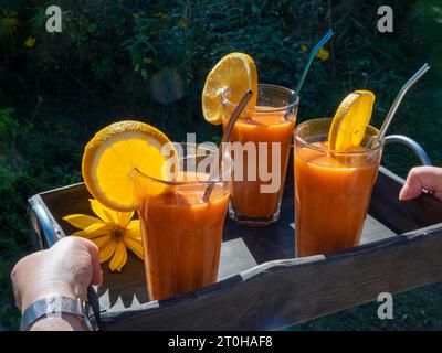 Freshly squeezed juice in juice glasses, carrots, lemon, apple, orange, health drink Stock Photo
