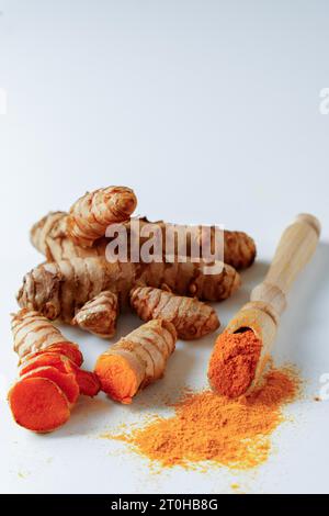 Fresh turmeric root and ground turmeric on a wooden spoon isolated on white background and copy space Stock Photo