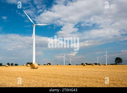 Windkraftanlagen auf einem abgeernteten Getreideacker  und Strohballen im Herbst Stock Photo