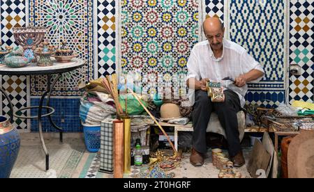 Fes, Morocco - 10 September 2022: Moroccan craftsman working with ceramics in a craft workshop to create pots, later to be displayed outside shops in Stock Photo
