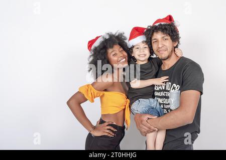 multiracial family posing with a child in their arms wearing Christmas hats, portrait Stock Photo