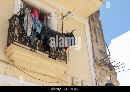 Low angle view of a clothesline in a balcony. There is also an antenna in the facade of the old building. Stock Photo