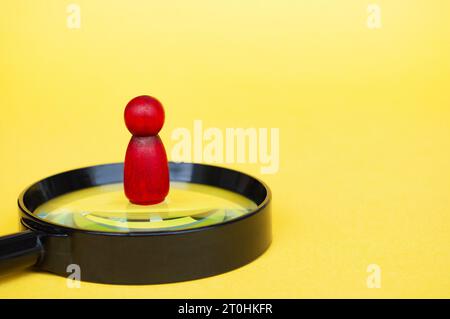 Wooden doll standing on magnifying glass with customizable space for text. Copy space. Stock Photo