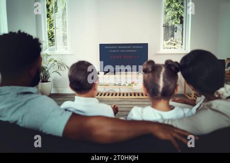 Back, family and watching tv for government announcement with people in their home during an emergency broadcast. Mother, father and children in the Stock Photo